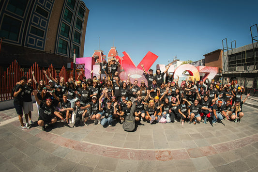 A large group of people in black t-shirts posing before a colorful city sign